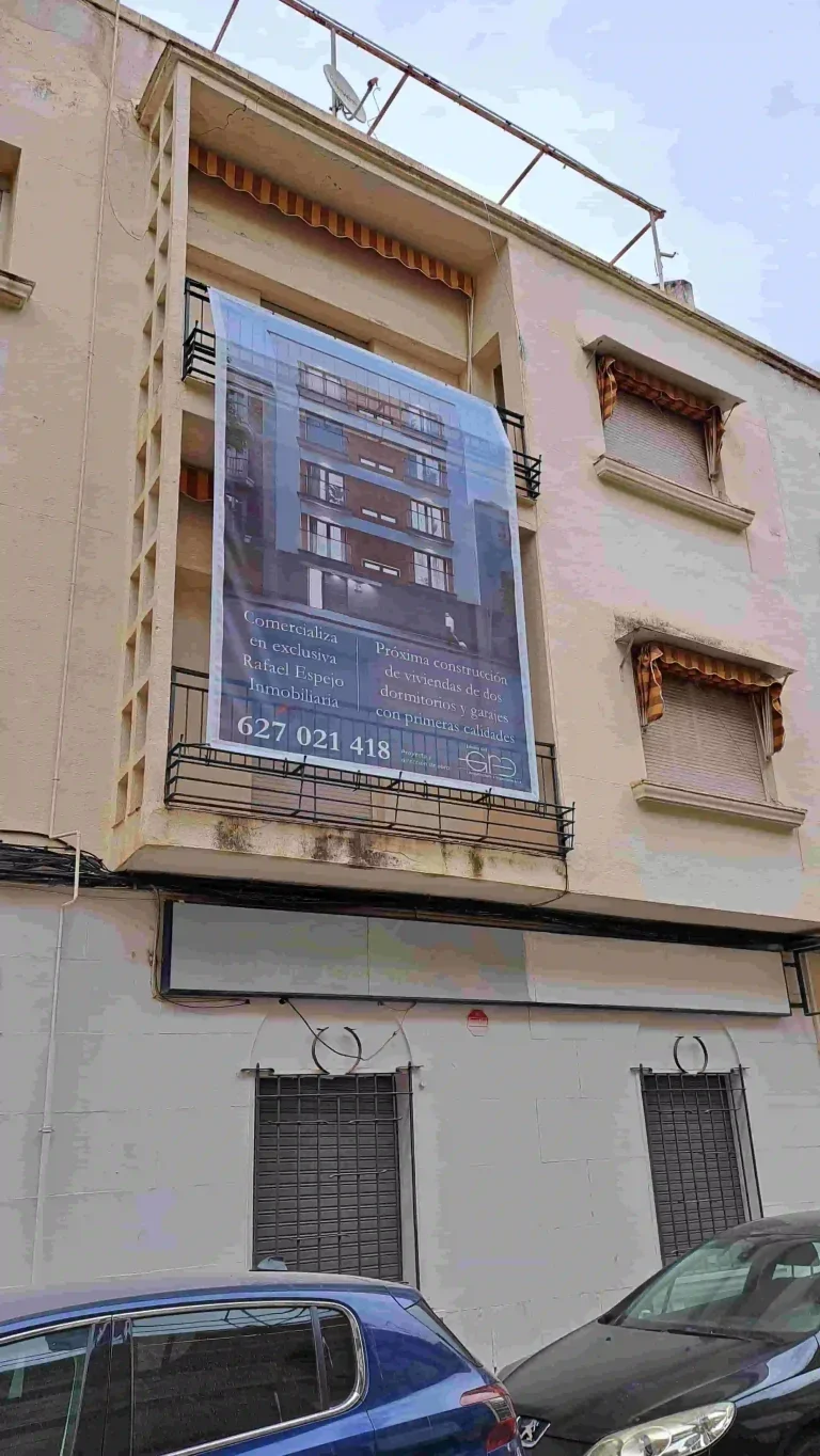 Lona microperforada de gran formato instalada en fachada para promocion inmobiliaria de empresa constructora con impresion digital exterior.