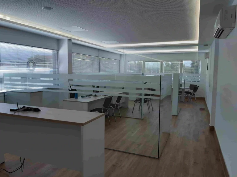 Oficina moderna decorada con vinilo ácido sobre mamparas de cristal, creando separación visual y privacidad en espacios de trabajo interiores.